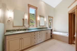 Bathroom featuring a built-in soaking tub, dual vanity with undermount sinks, and two framed mirrors