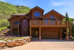 Multi-level wood-clad exterior featuring multiple balconies, a lower-level garage, and a stacked stone retaining wall
