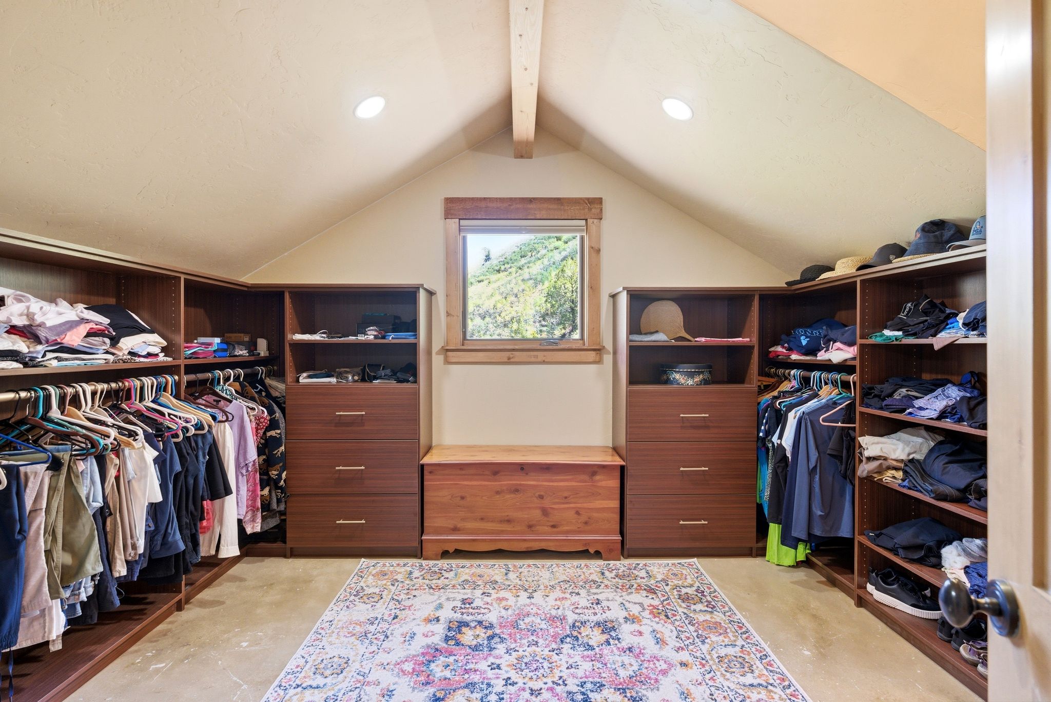 Attic conversion featuring vaulted ceilings with exposed beam, recessed lighting, wood-framed window, and built-in wood-finish closet organizational systems