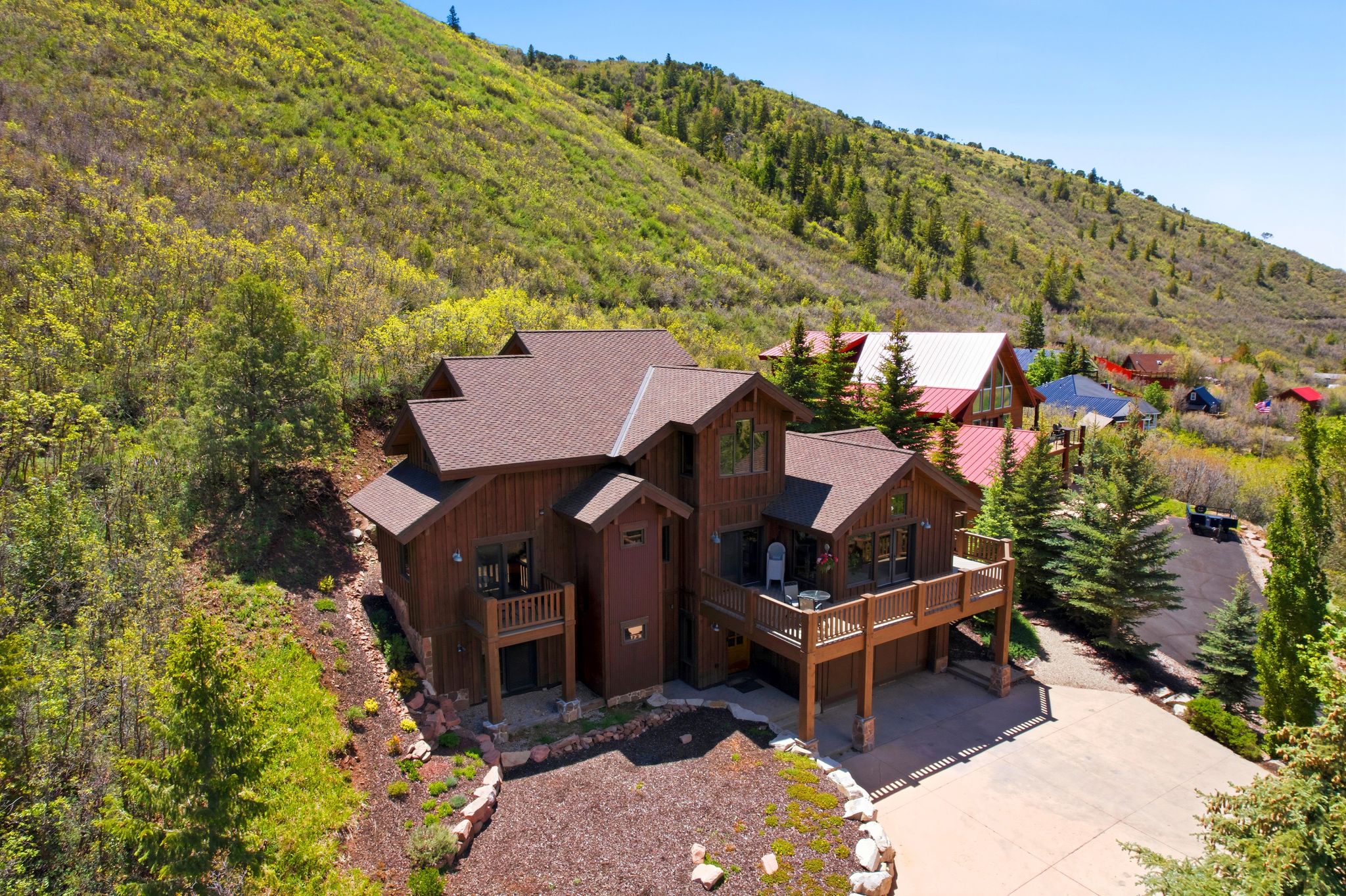 Multi-level residence featuring a brown wood-paneled exterior, dark brown shingle roof, and multiple outdoor deck spaces