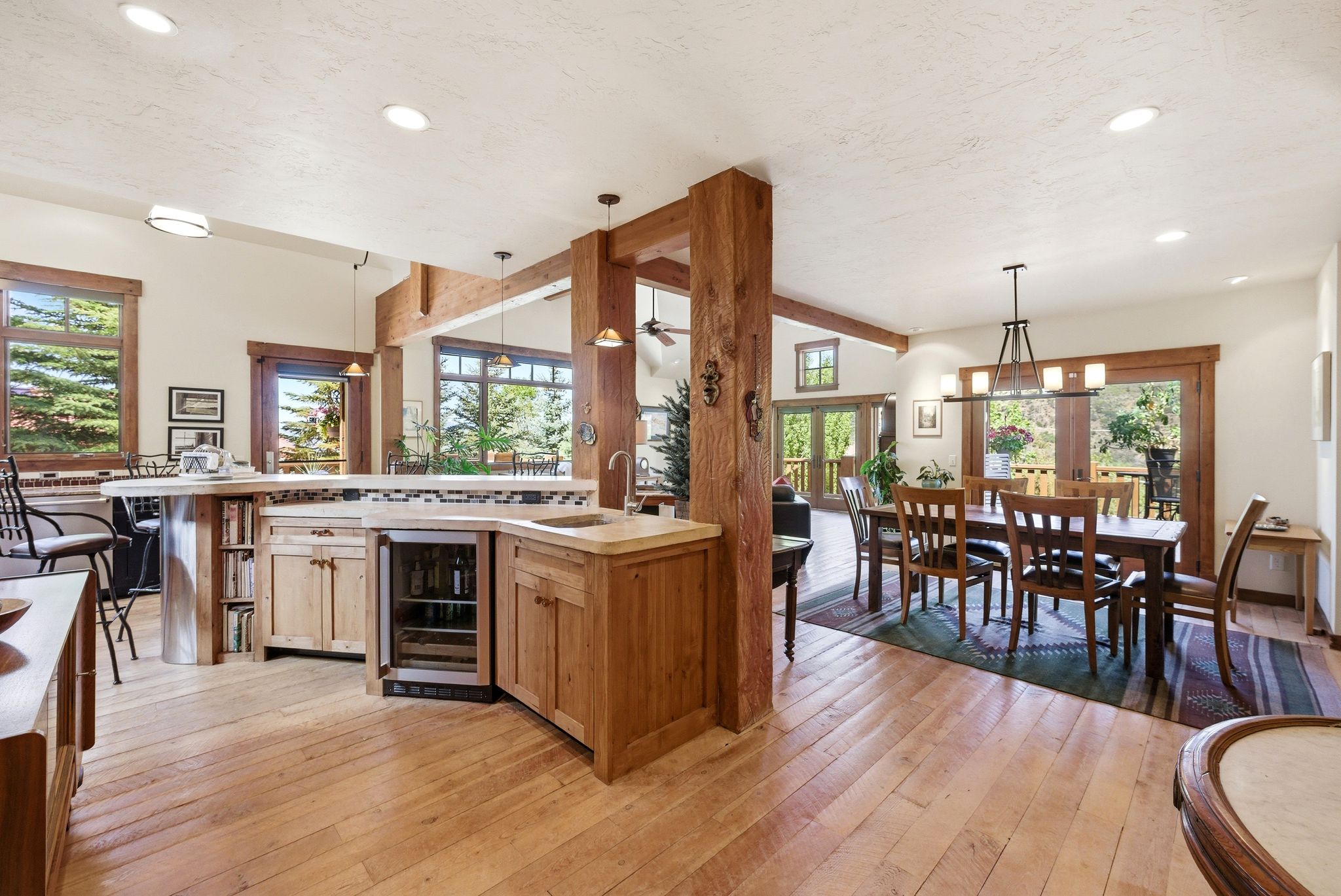 Open-concept living area featuring blonde wood-finish flooring, exposed wood beams, and recessed lighting