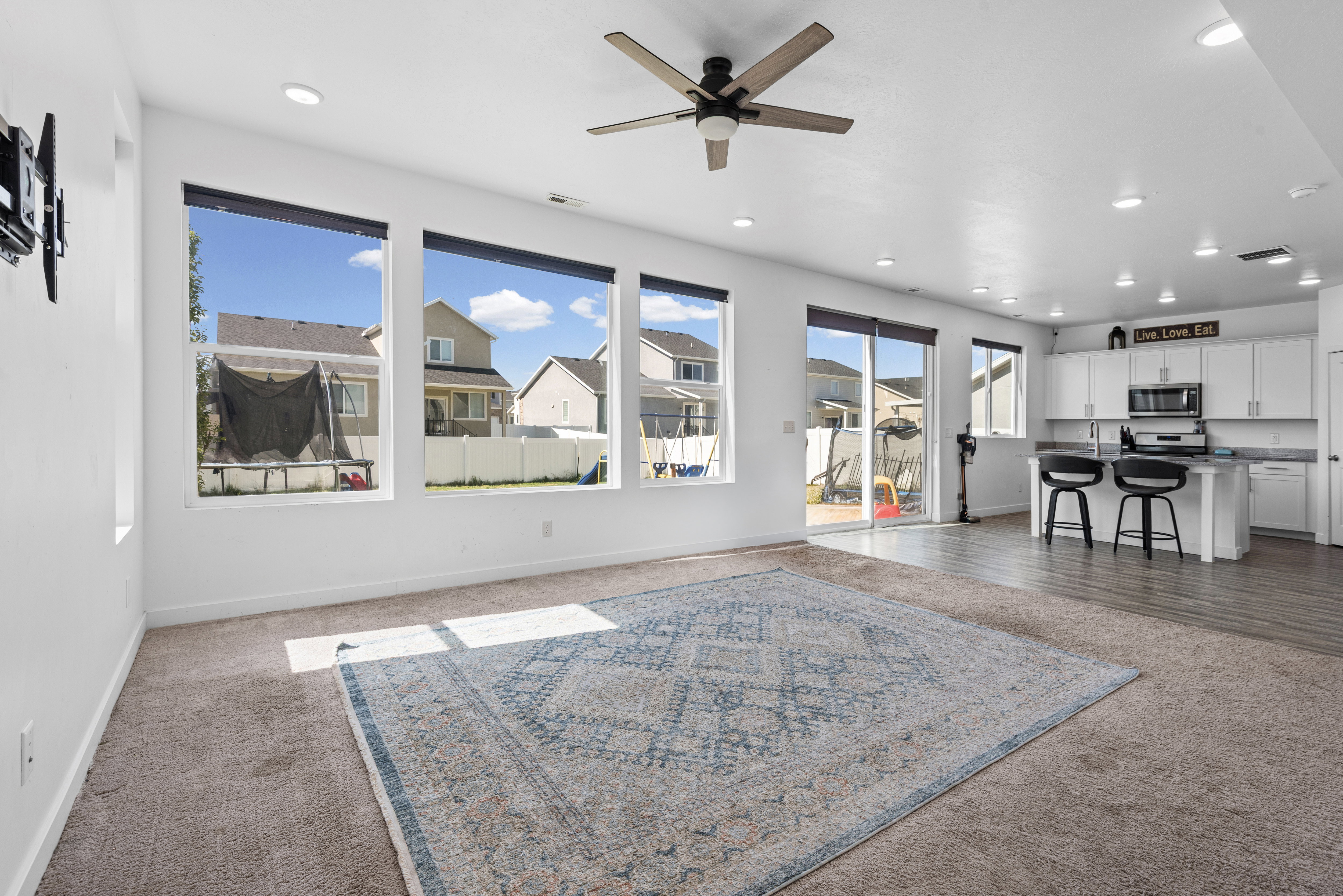 Spacious open-concept interior featuring large windows, recessed lighting, and a ceiling fan