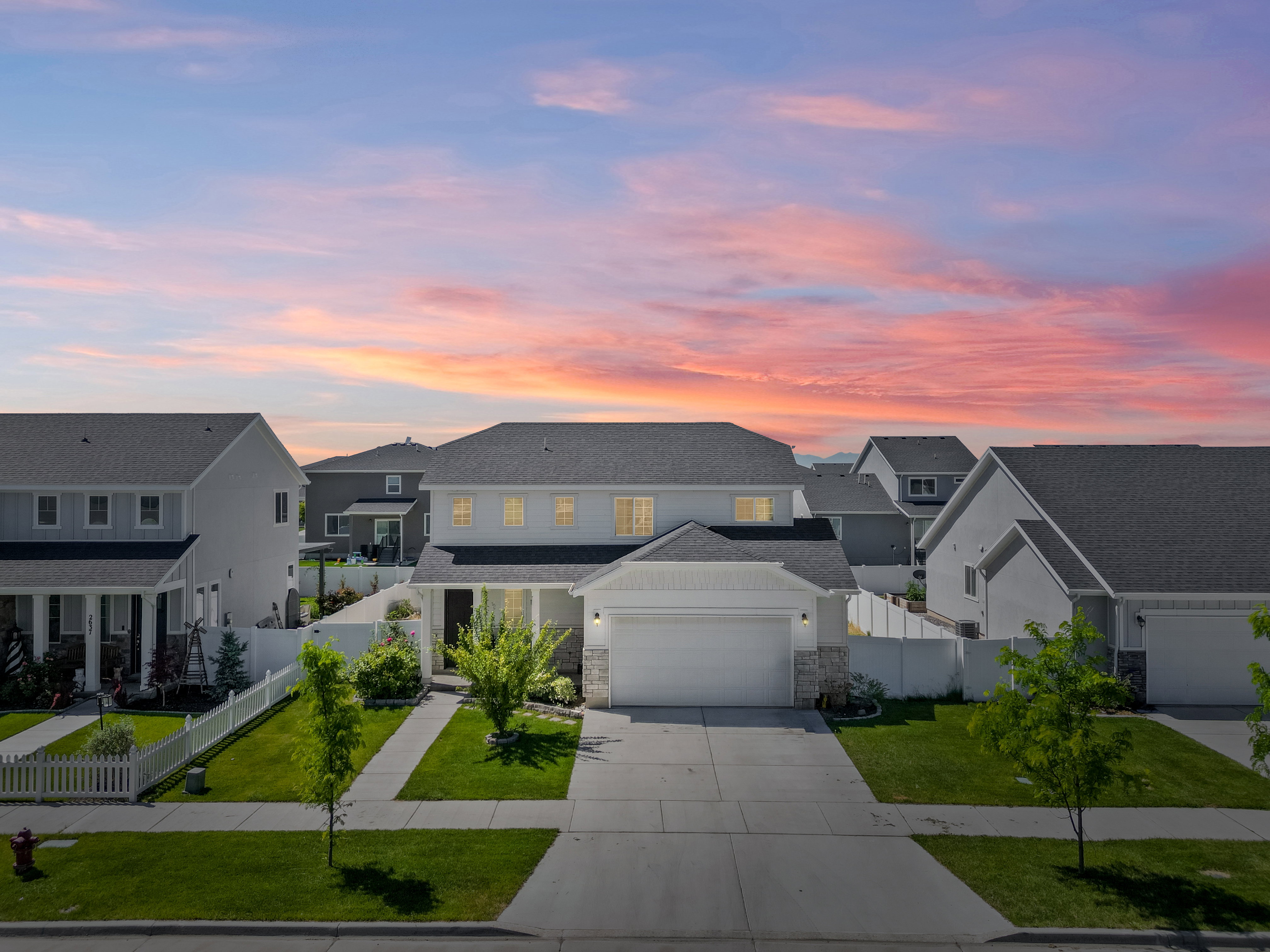 Contemporary two-story residence featuring a white siding exterior with stone accents and a dark shingle roof