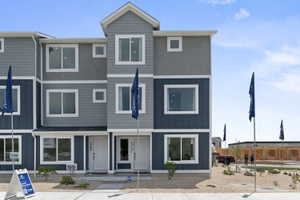 Contemporary townhome exterior featuring multi-level architecture with blue vertical siding and light gray stucco finishes