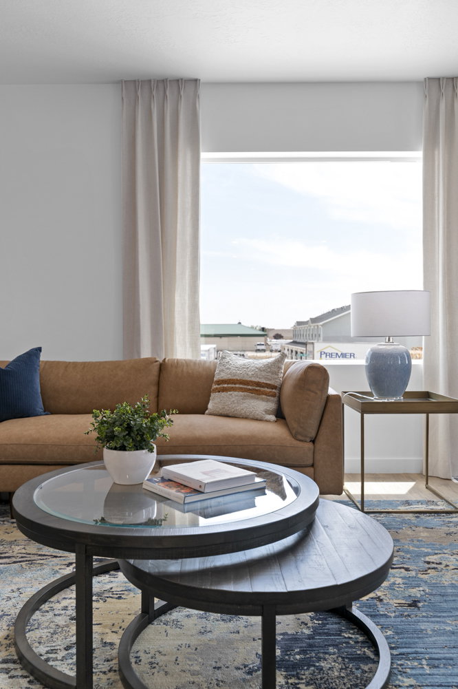 Bright living space featuring a large window with natural light, light-toned drapery, and neutral-colored walls