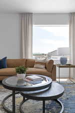 Bright living space featuring a large window with natural light, light-toned drapery, and neutral-colored walls