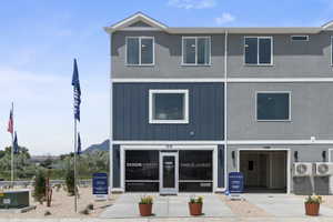 Contemporary townhome exterior featuring a blue vertical siding accent, light gray stucco, and white trim