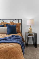 Clean white wall with neutral carpet flooring, featuring a black metal bed frame