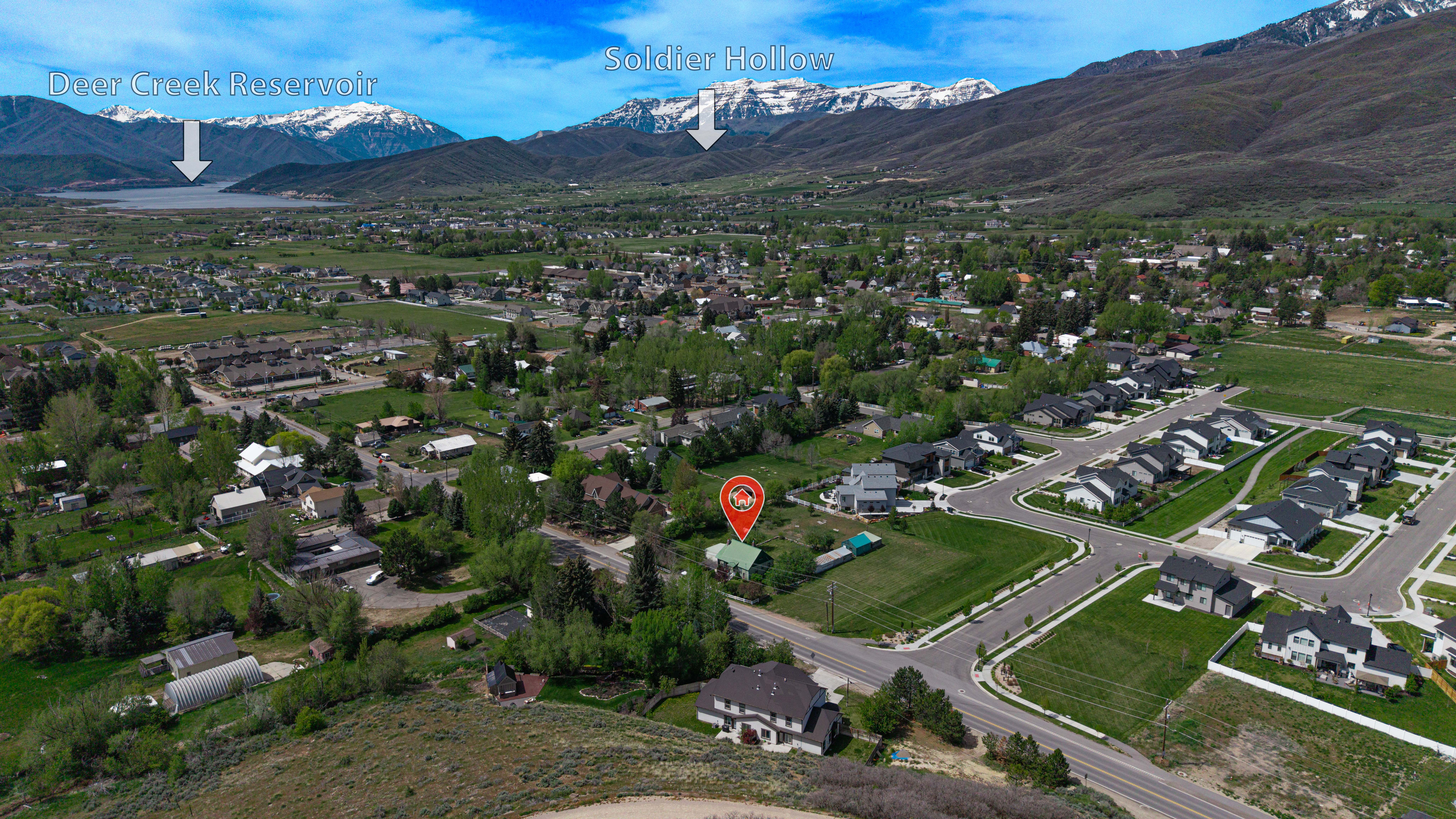 Aerial perspective showcasing a residential area framed by distant snow-capped mountains and a prominent body of water