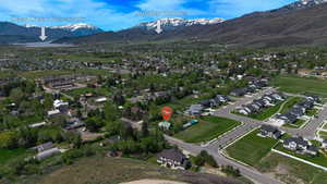 Aerial perspective showcasing a residential area framed by distant snow-capped mountains and a prominent body of water