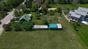 Expansive grassy lot with established trees and two outbuildings