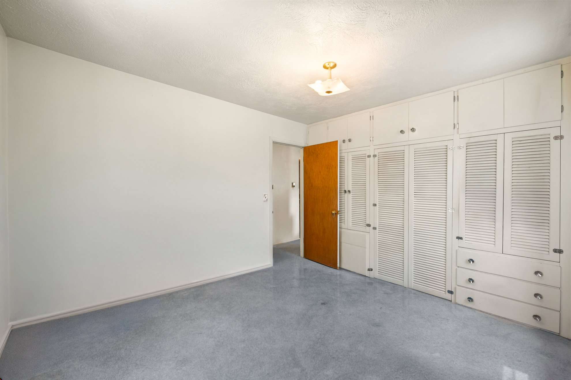 Built-in white cabinetry with louvered doors and drawer storage