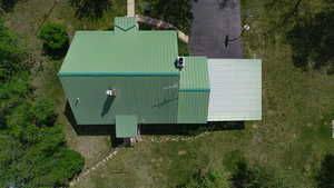 Property featuring a vibrant green metal roof, a contrasting light-colored extension roof, and a paved driveway