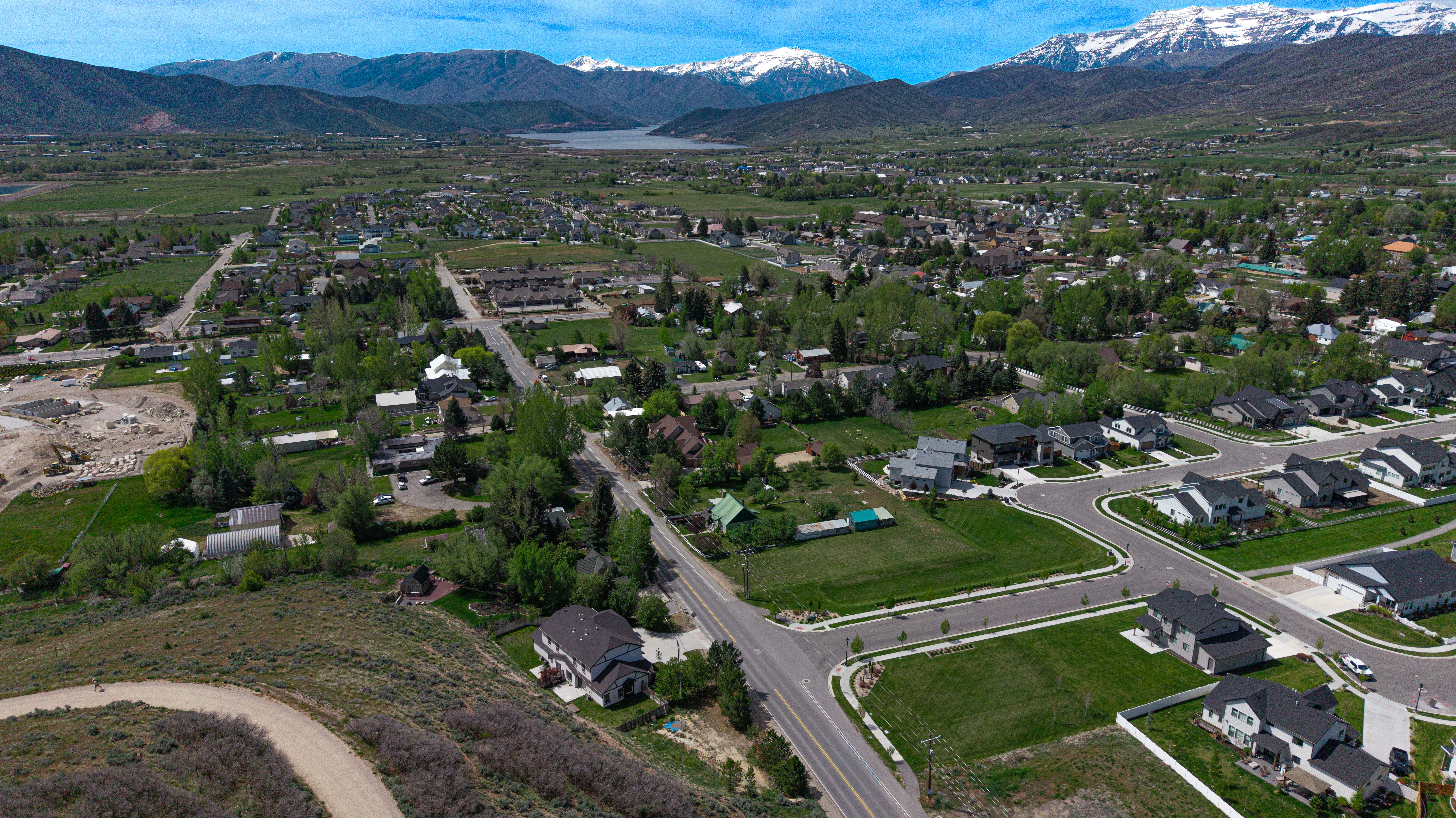 Expansive residential landscape featuring a mix of established homes and new construction, set against a backdrop of distant, snow-capped mountains and a prominent body of water