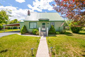 Single-story home featuring a green metal roof, light green siding, and a covered carport