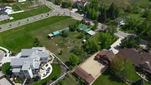 Expansive property featuring multiple structures, verdant green lawns, mature trees, a gravel parking area, and a paved street