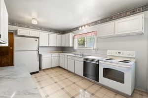 Kitchen featuring white cabinetry, white countertops, built-in sink, white refrigerator, and a white electric range with an oven
