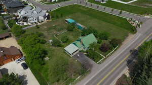 Expansive property featuring a green-roofed residence, extensive grassy areas, and mature trees