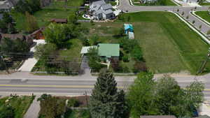 Property featuring a green metal roof, a white picket fence, a gravel driveway, a detached shed, and mature trees