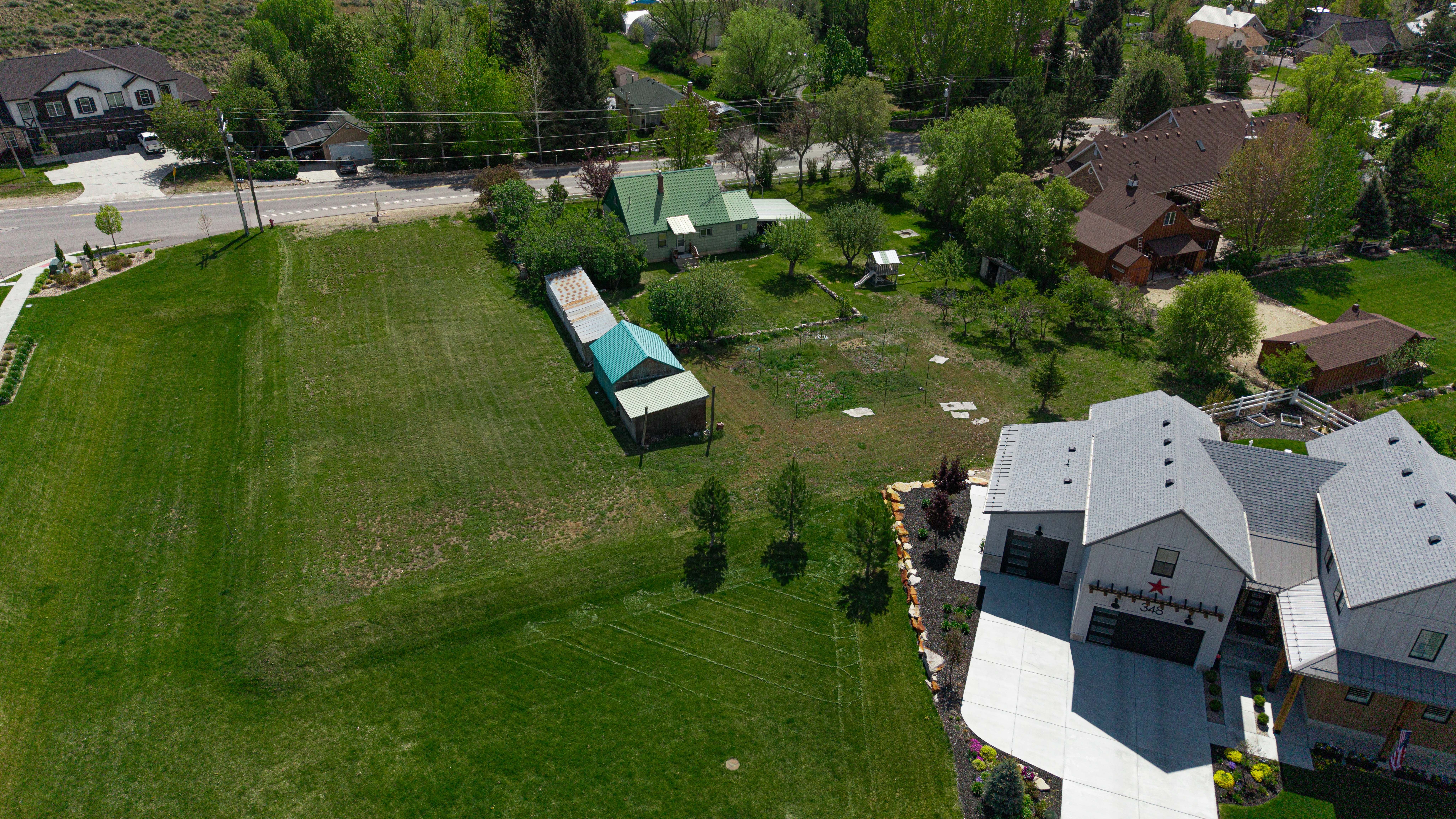Expansive grass lot with mature trees, offering a street-front location and proximity to developed residential properties