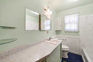 Bathroom featuring a vanity with an integrated sink, a wall-mounted mirror, and glass shelving