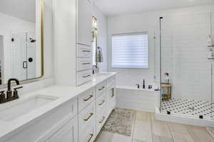 Bathroom featuring dual vanity with white cabinetry and gold-tone hardware, rectangular undermount sinks, and dark bronze fixtures