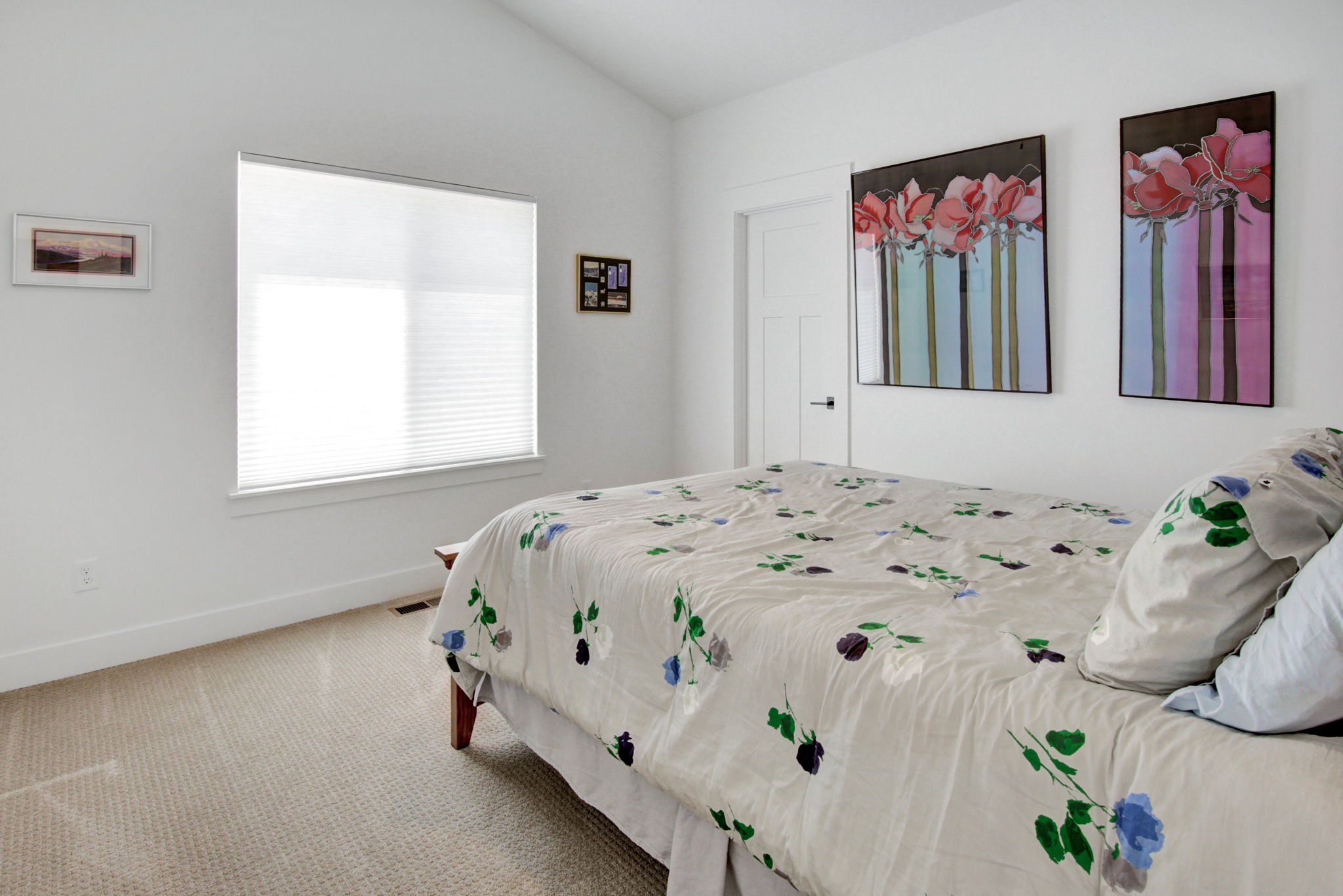 Carpeted room featuring a large window with privacy blinds, vaulted ceilings, and a solid core door