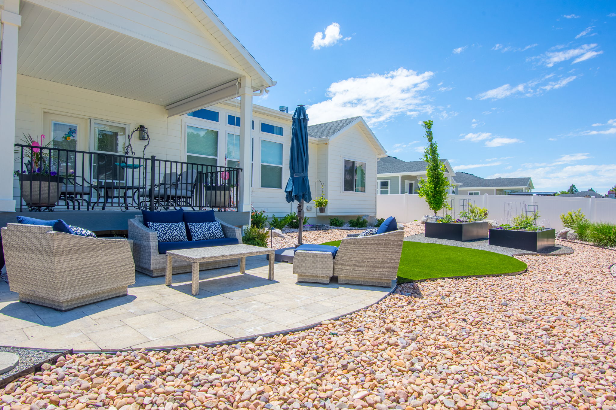 Expansive paver patio with a curved edge, featuring a covered porch with black metal railing