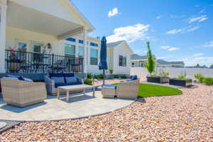 Expansive paver patio with a curved edge, featuring a covered porch with black metal railing