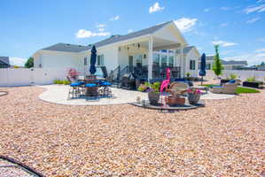 Expansive backyard featuring a large gravel area, two distinct patio spaces, a covered patio with architectural columns, and white vinyl fencing