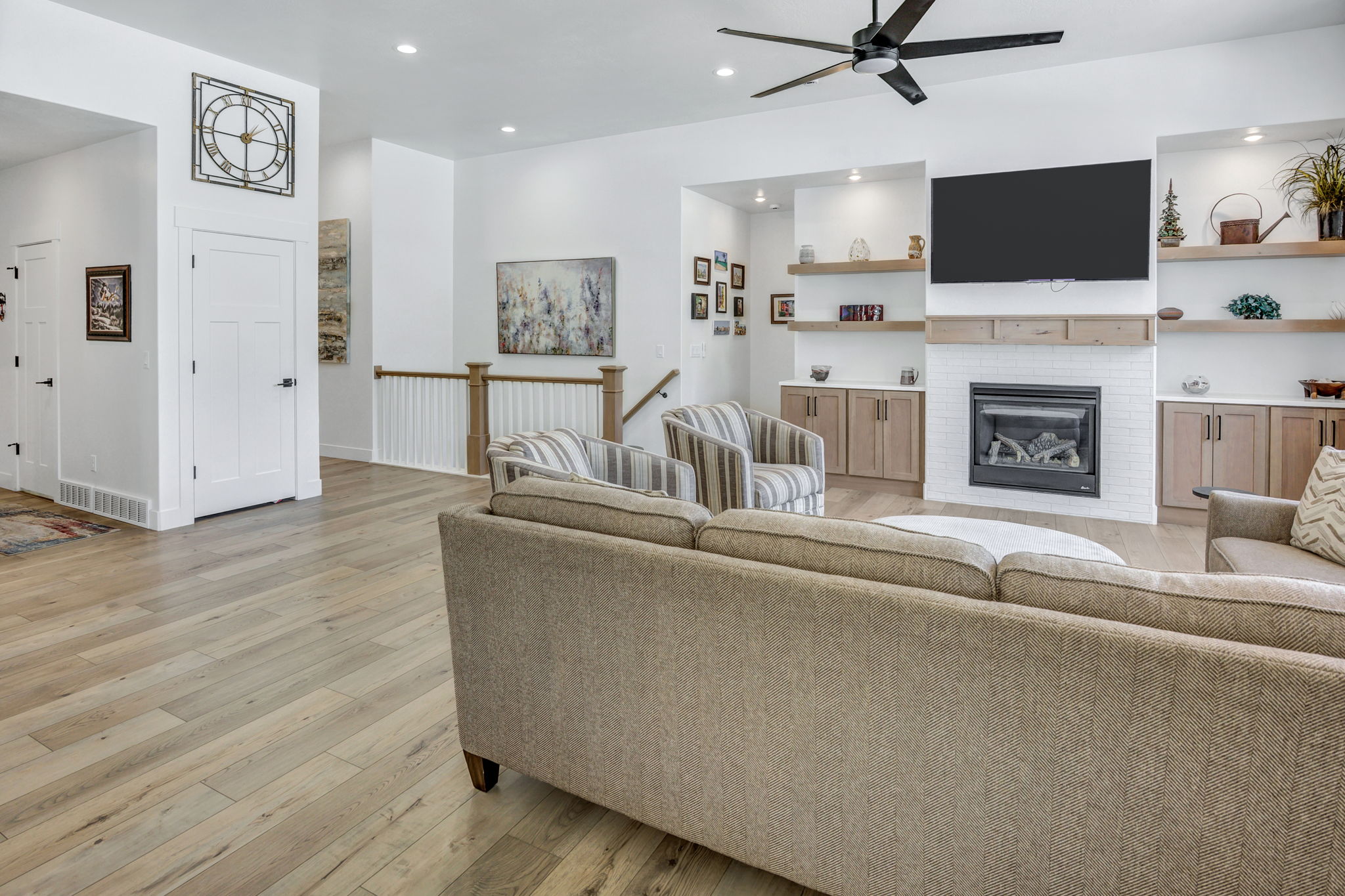 Spacious living area featuring light LVP flooring, a contemporary ceiling fan, and recessed lighting