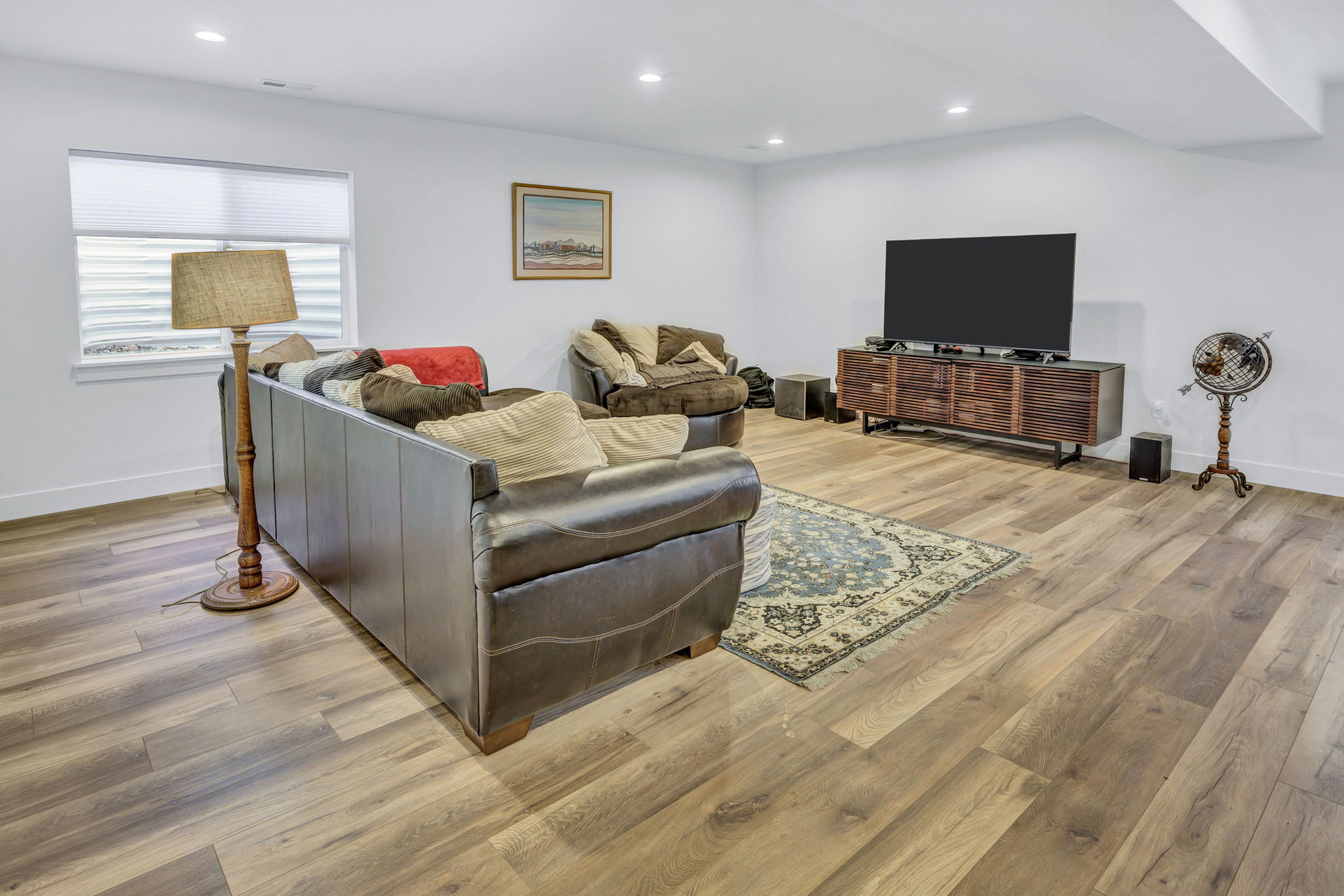 Spacious living area featuring LVP flooring, recessed lighting, white walls, and a window with horizontal blinds