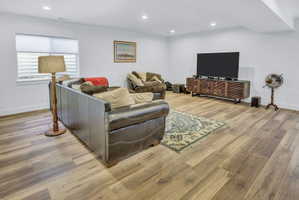 Spacious living area featuring LVP flooring, recessed lighting, white walls, and a window with horizontal blinds
