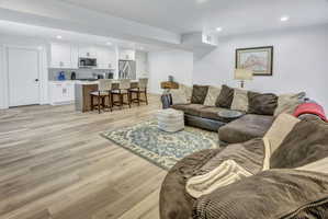 Open-concept living area featuring LVP flooring, recessed lighting, and a white kitchen with an island and stainless steel appliances