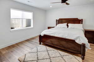Spacious bedroom featuring LVP flooring, a contemporary ceiling fan with integrated lighting, recessed overhead lighting, and a window with blinds