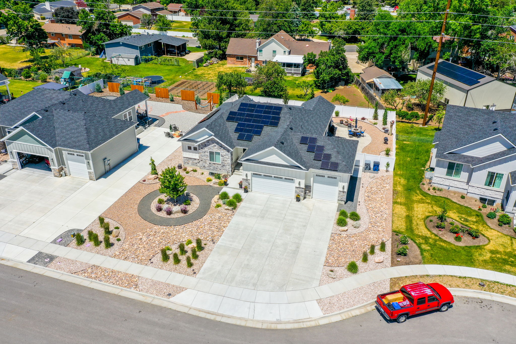 Modern residence featuring a stone and siding exterior, a multi-car driveway, and a Xeriscaped front yard with decorative plantings