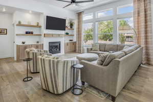 Living space featuring LVP flooring, a white tiled fireplace, built-in cabinetry, floating wood shelves, and large pane windows