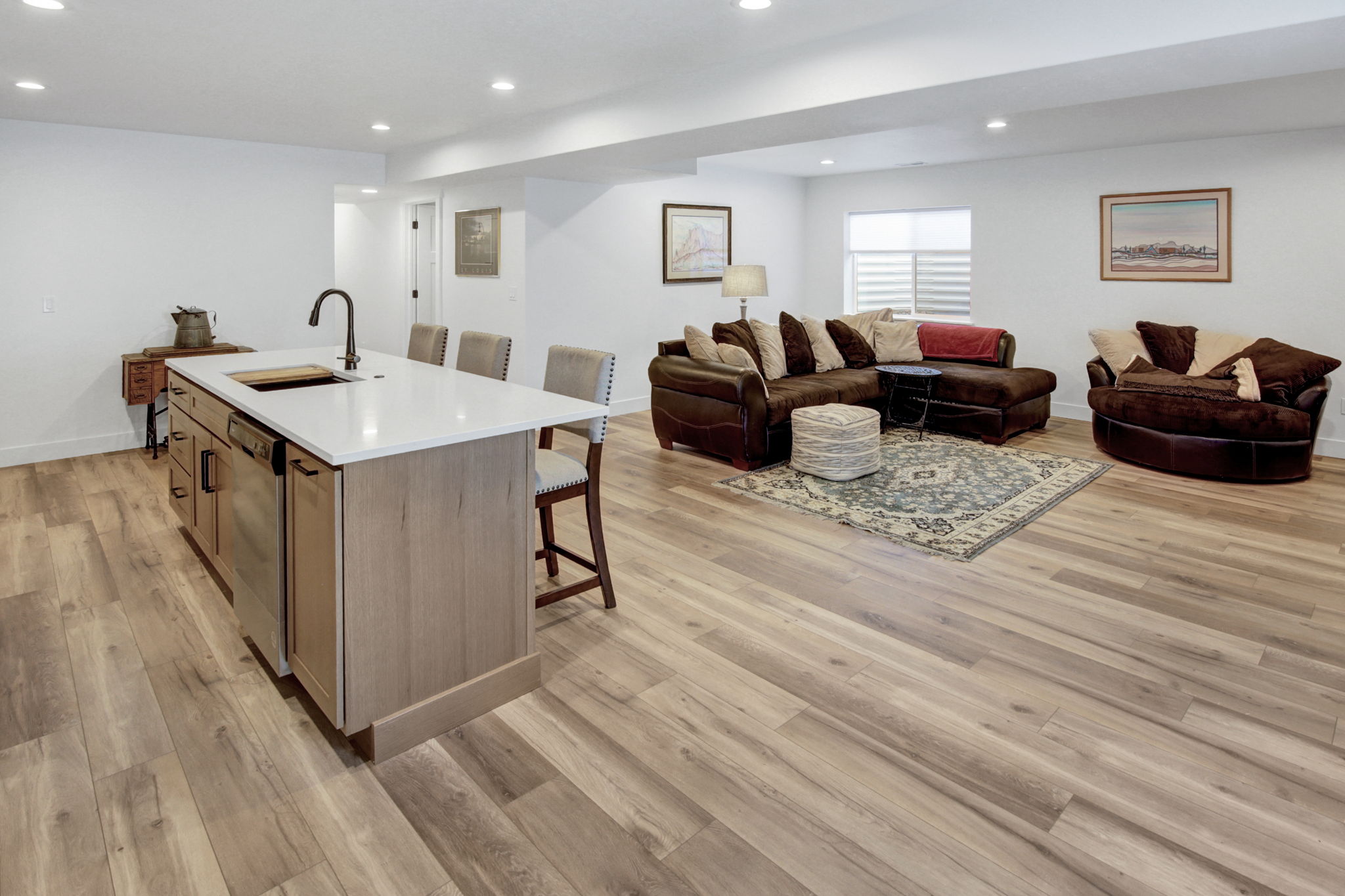 Open-concept living area featuring LVP flooring, recessed lighting, and a kitchen island with seating