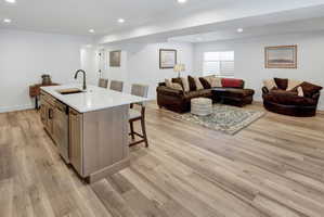 Open-concept living area featuring LVP flooring, recessed lighting, and a kitchen island with seating