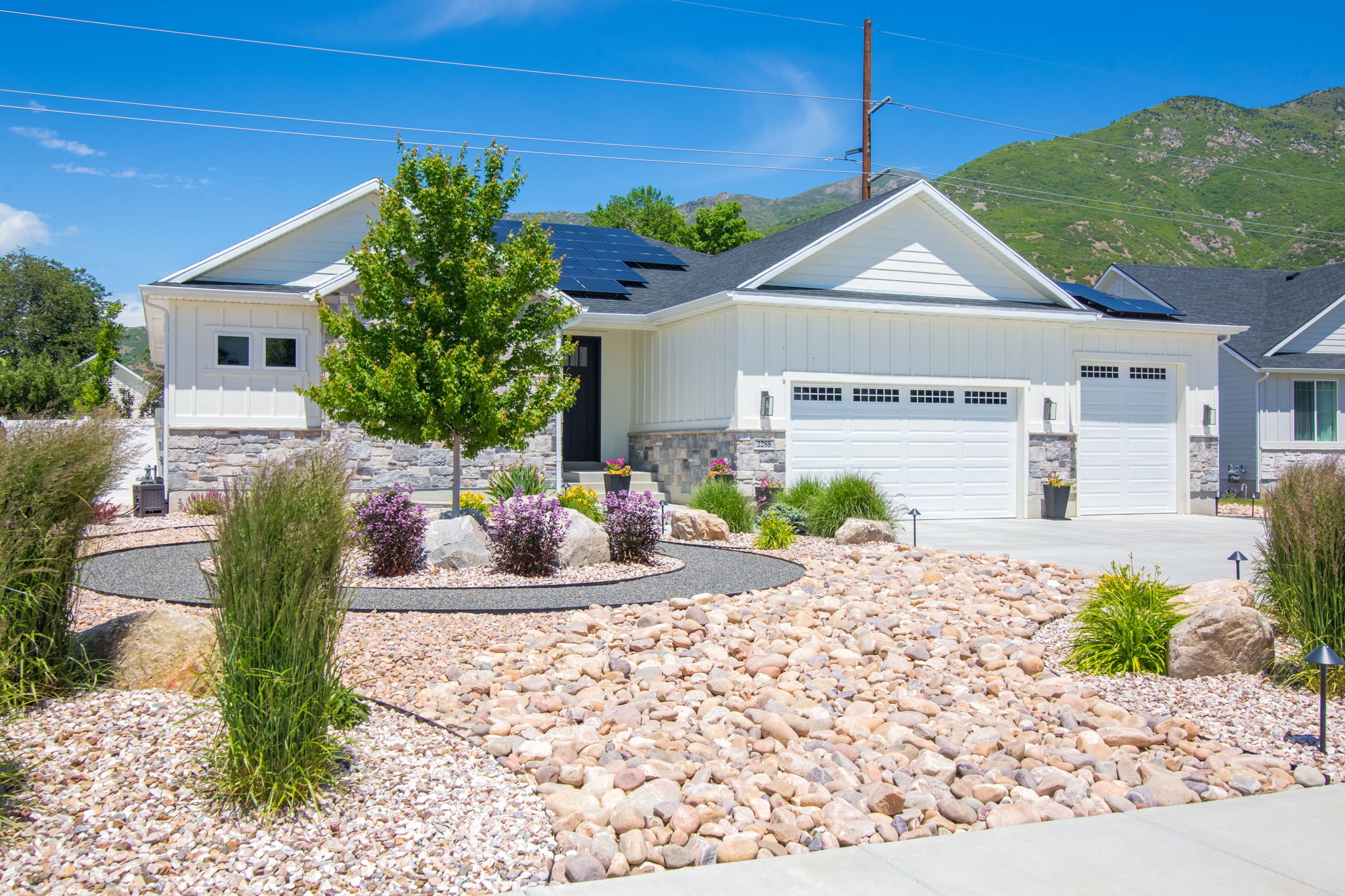 Modern ranch-style exterior featuring white vertical siding and stone veneer accents