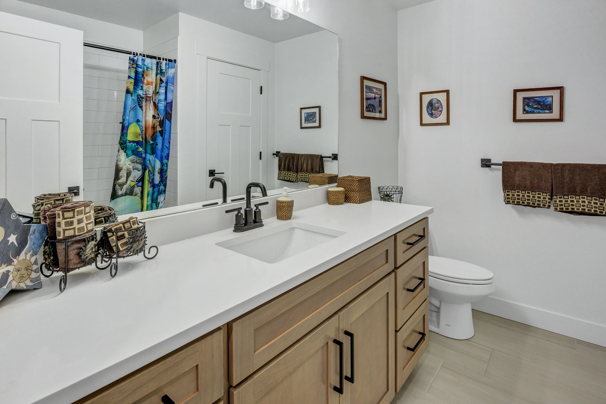 Bathroom featuring a light wood-finish vanity with ample storage, a clean white countertop, and a single undermount sink
