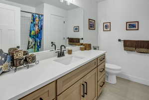 Bathroom featuring a light wood-finish vanity with ample storage, a clean white countertop, and a single undermount sink