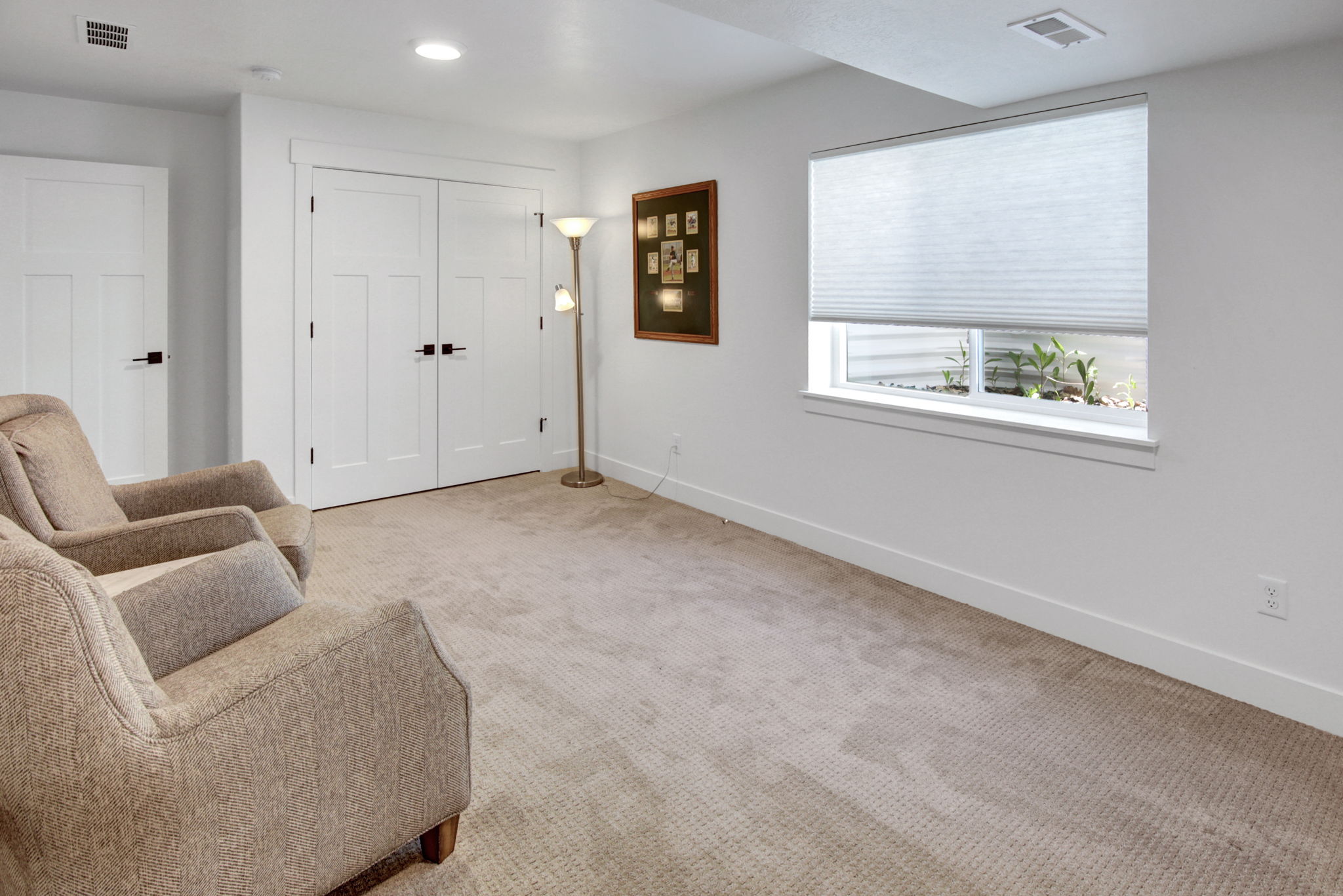 Neutral-toned carpeting extends throughout this interior space, featuring a window with a cellular shade