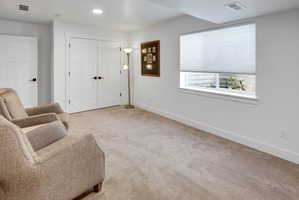 Neutral-toned carpeting extends throughout this interior space, featuring a window with a cellular shade