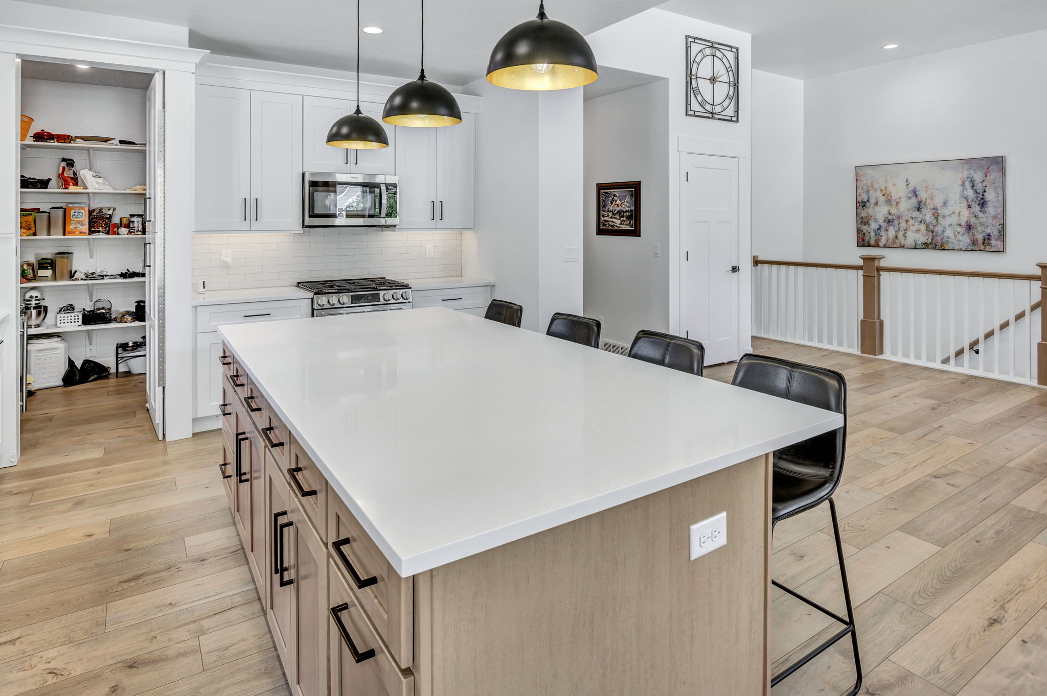Modern kitchen featuring a large central island with quartz countertop, white cabinetry, a subway tile backsplash, stainless steel appliances, and LVP flooring