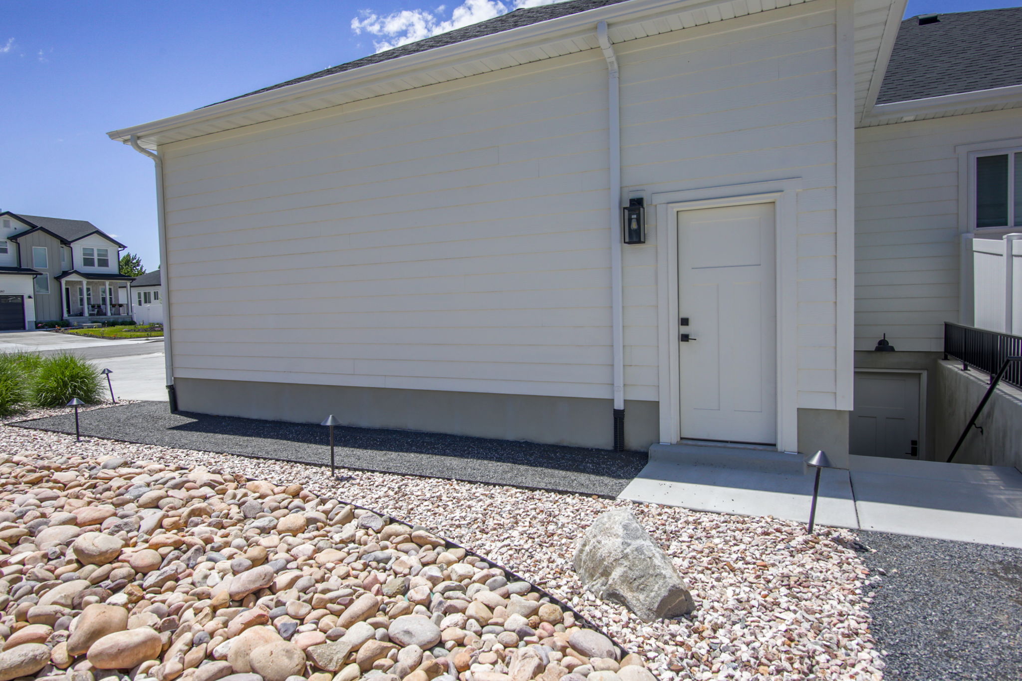 Side entry featuring a panel door with black hardware, an exterior wall lantern, and a concrete stoop
