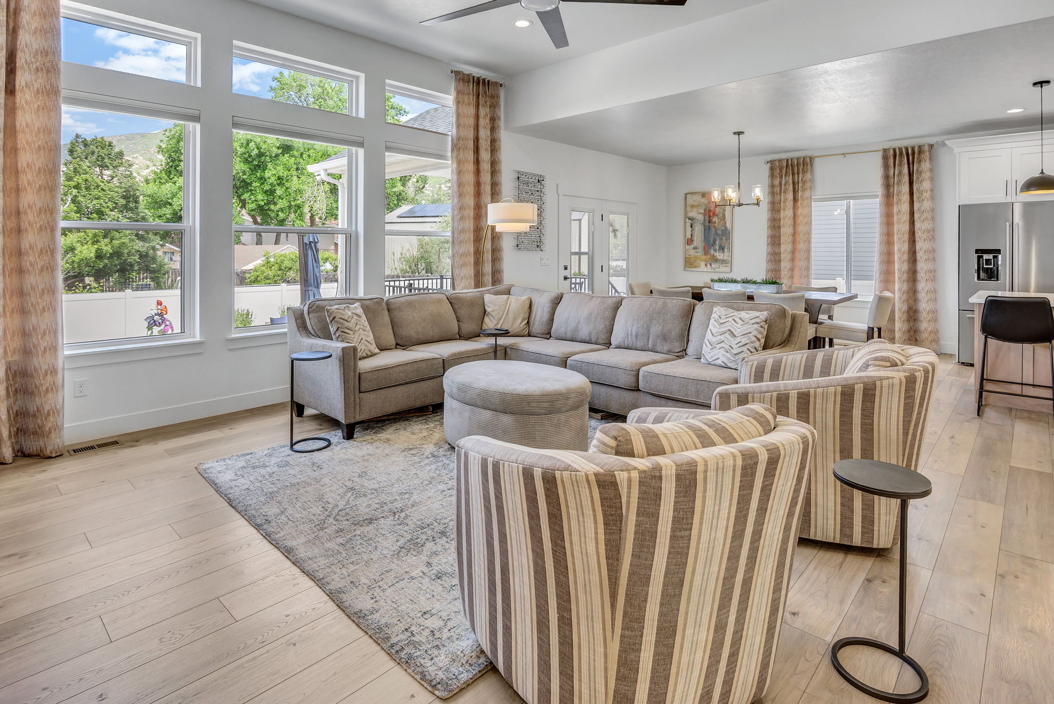Spacious living area featuring large picture windows, LVP flooring, a ceiling fan, and recessed lighting
