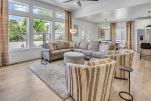 Spacious living area featuring large picture windows, LVP flooring, a ceiling fan, and recessed lighting