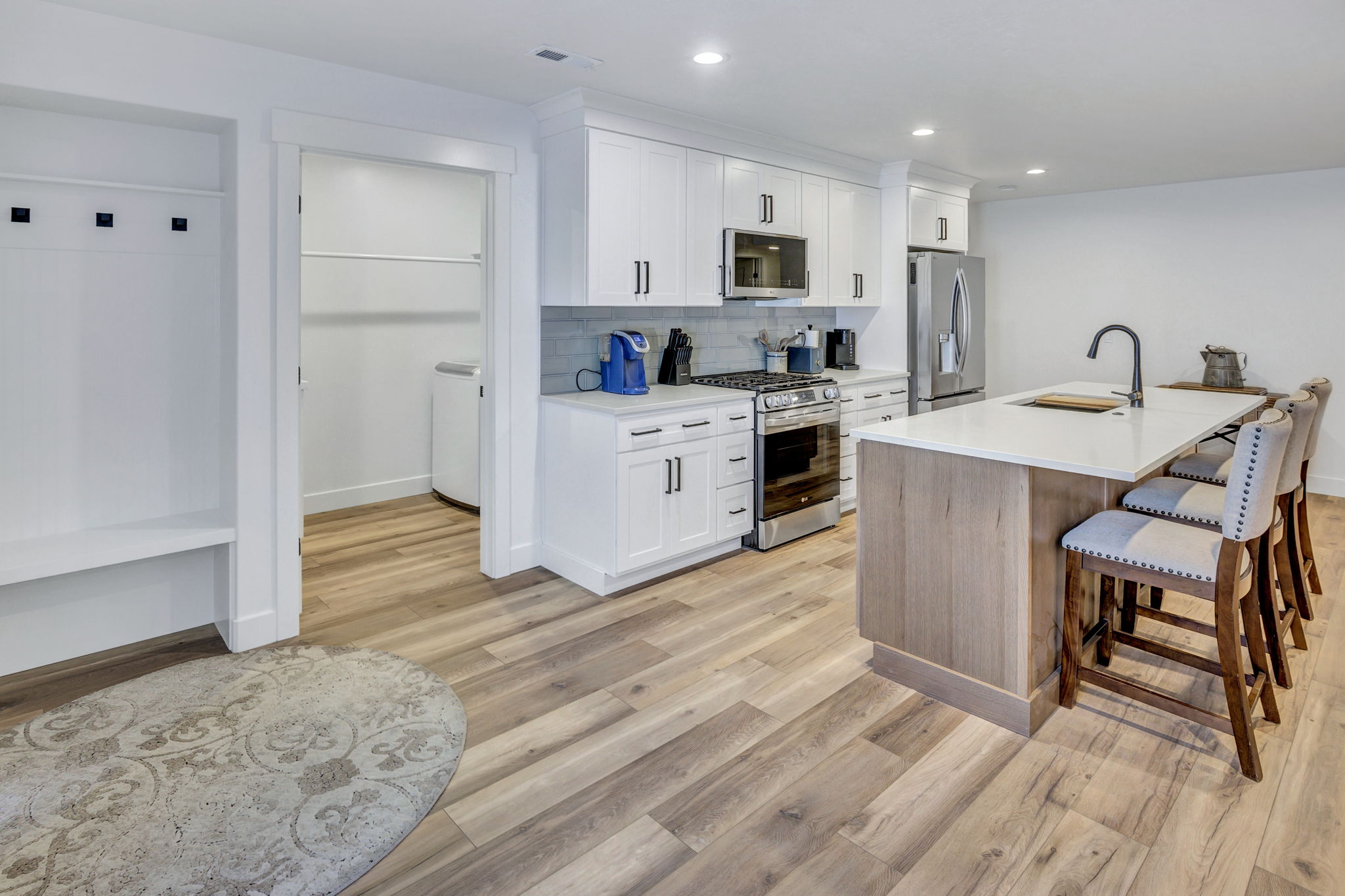 Modern kitchen featuring white cabinetry, stainless steel appliances, a white island countertop, and LVP flooring