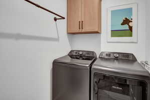 Laundry area featuring a wall-mounted drying rod and light wood-finish cabinetry